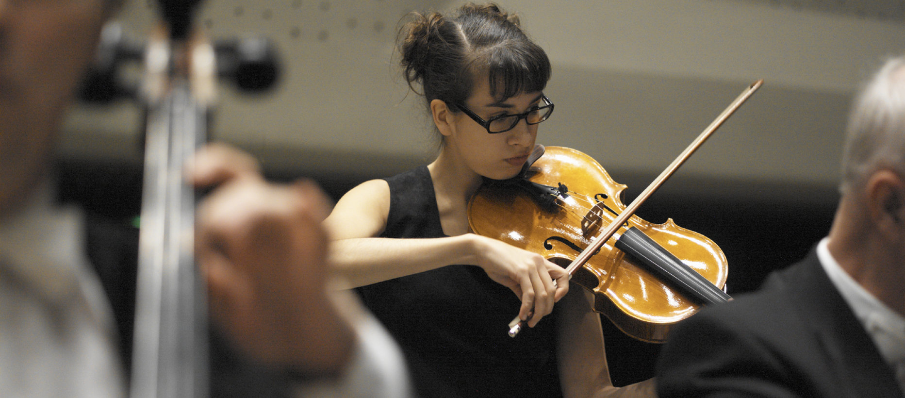 Lähikuva naisesta, joka soittaa viulua orkesterissa. Kuvituskuva.