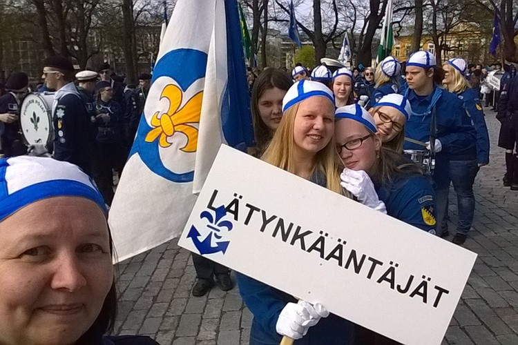 Nuoria partiolaisia valmistautumassa lippujen kanssa partiomarssille