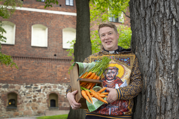 Tuomiokirkon edustalla, pastori Tuomas Vaura, sylissä porkkanoita.