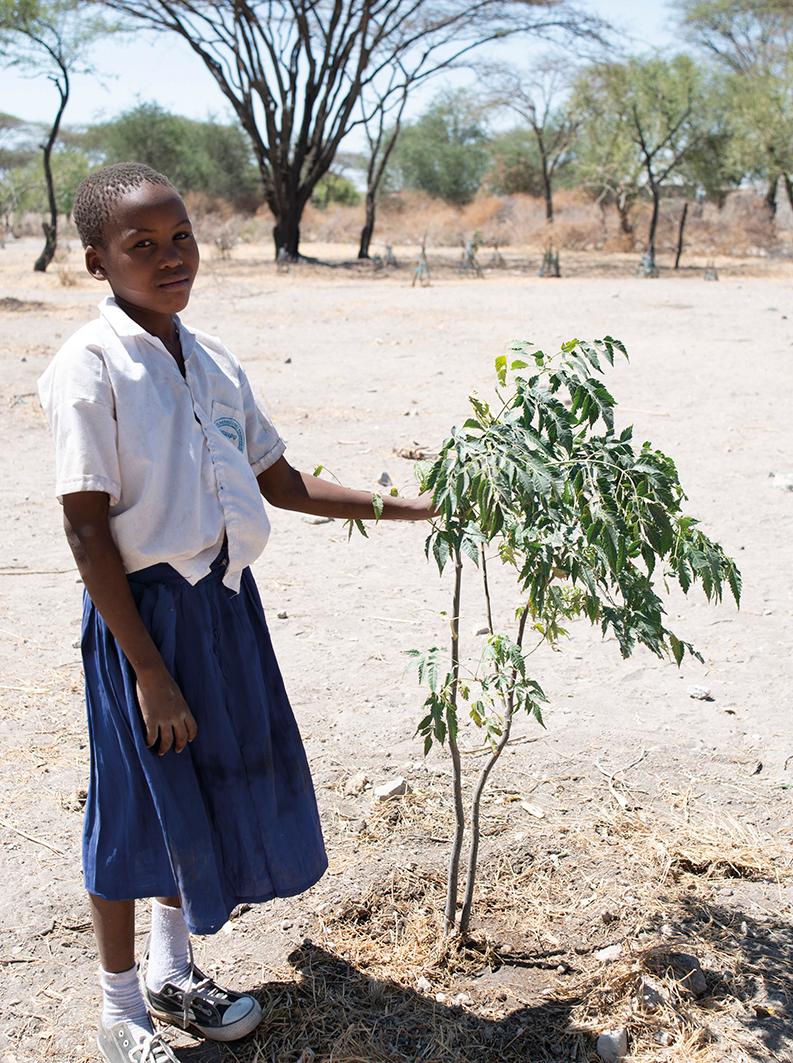 Rozimary Gambishi esittelee istuttamaansa puuta Tansaniassa.