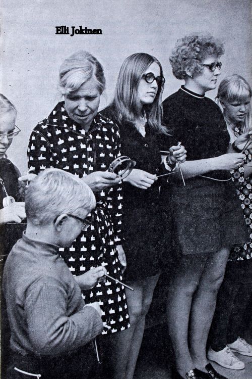 Mustavalkoinen kuva. Sisar Elli Jokinen ja kehitysvammaisia lapsia musiikkikerhossa. Kädessä rytmisoittimia.