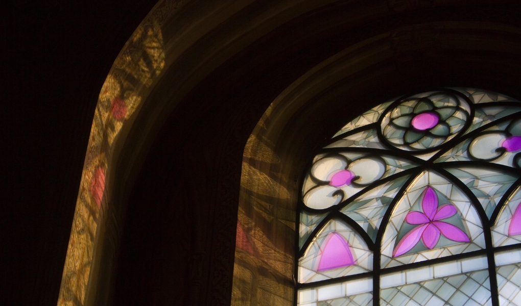 Tuomiokirkon ikkunan lasimaalaukset heijastuvat hämärässä valossa kirkon seinille.