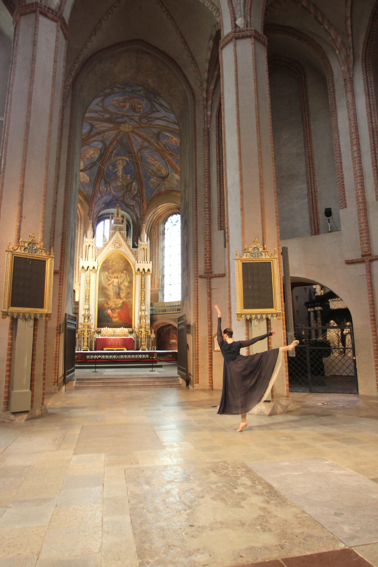 Nainen tanssii Turun tuomiokirkon holvien alla. Taustalla näkyy kirkon alttaritaulu.