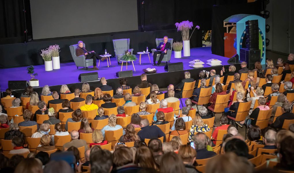 Lava, jolla kaksi keskustelijaa ja auditorion katsomo täynnä ihmisiä.