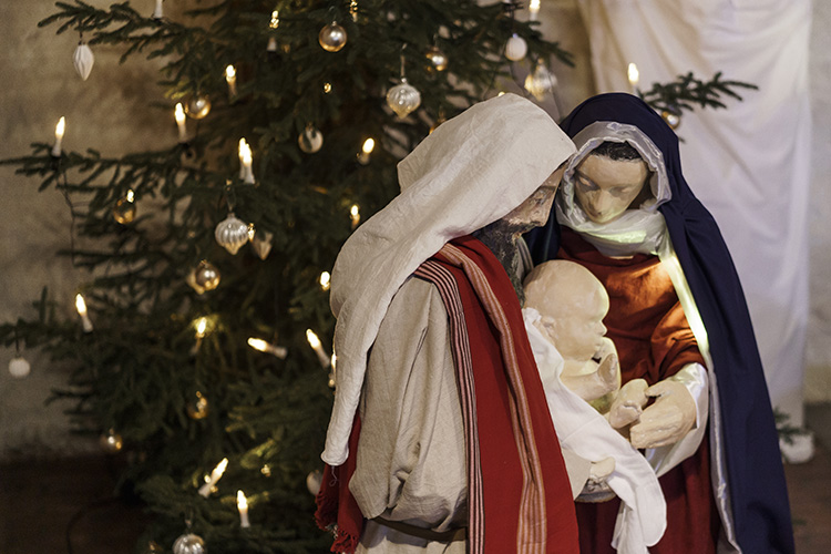 Ihmisen kokoiset nukkehahmot Joosefista, Mariasta kumartuneena Jeesus-lapsen puoleen.