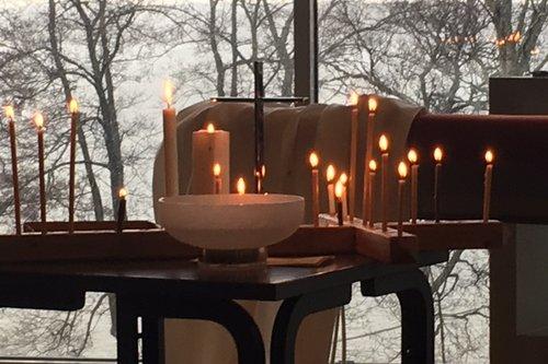 Sinapin kappelissa pöydällä tuohusristi ja kynttilöitä ja kastemalja