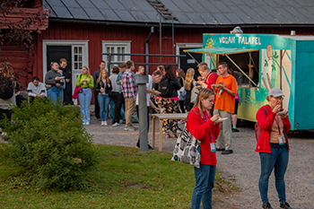 Food & Hope Joukko nuoria aikuisia seisomassa ruokakojun ympärillä ja syömässä katuruokaa.