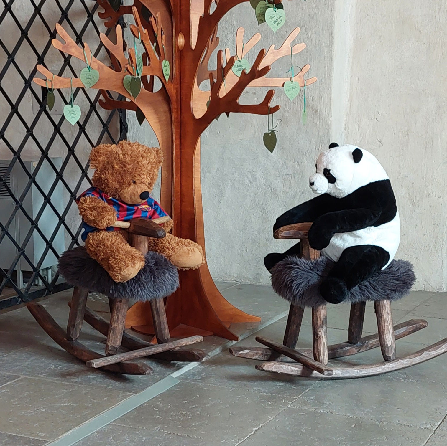 Pehmolelut Leo-nalle ja Tempo-panda istuvat keinulampaiden päällä Tuomiokirkossa kastepuun edessä.