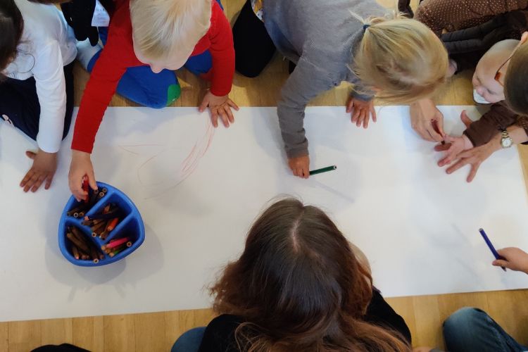Lapsia ja aikuisia piirtää lattialla paperille