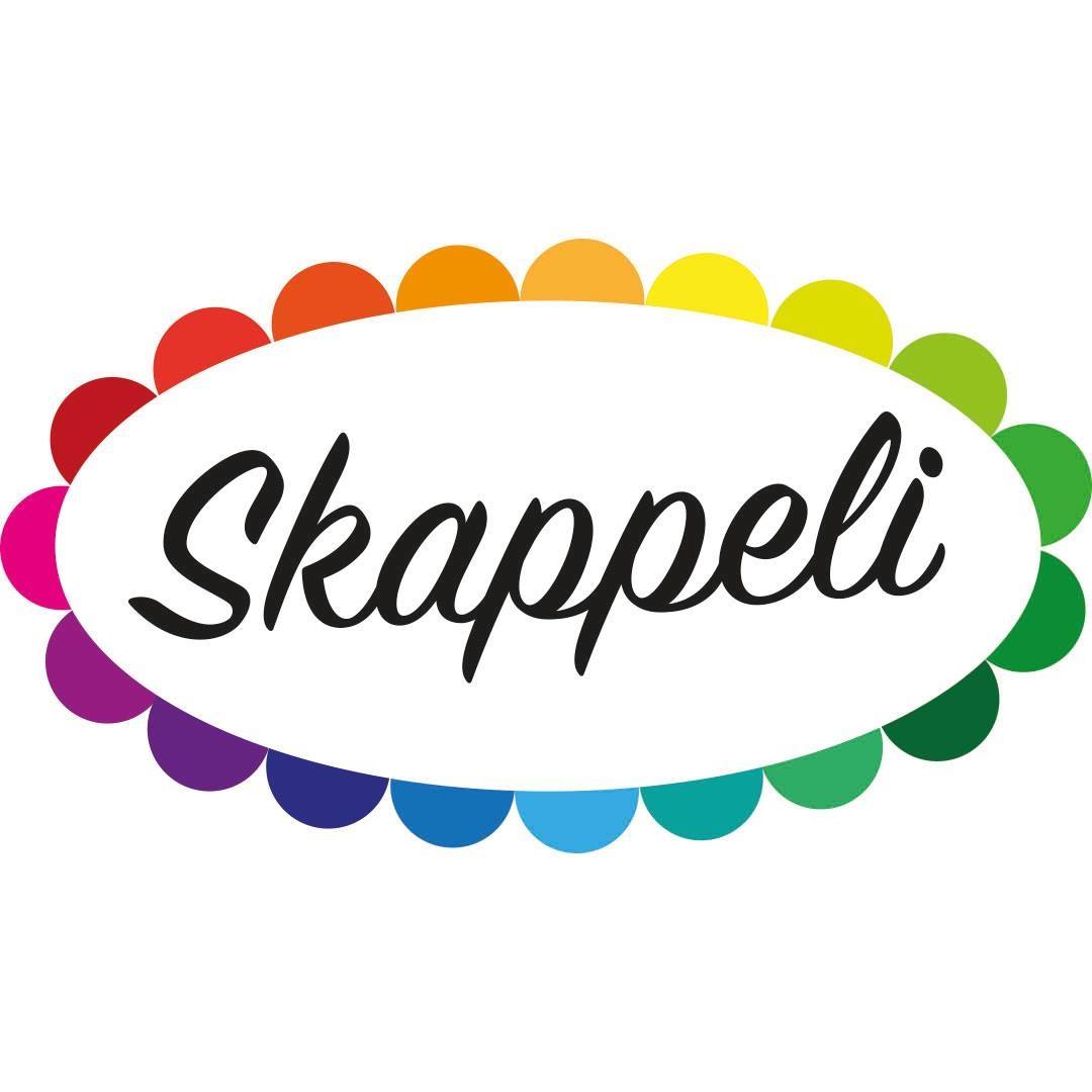 Skappelin maanatait Soikea kukka, eriväriset terälehdet, keskusta valkoinen siinä mustalla kirjoitettu Skappeli