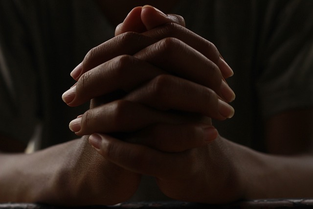 Kuvassa rukoilevat kädet ristissä.