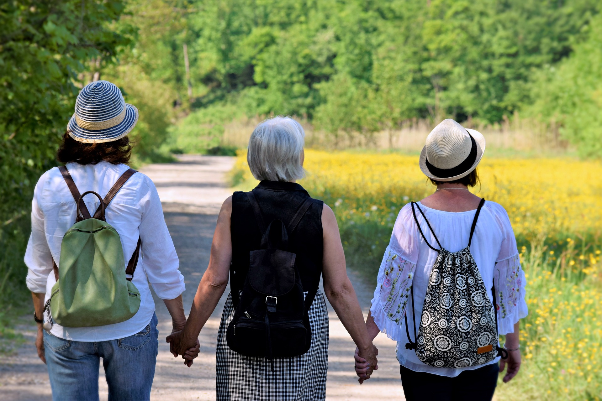 kolme naista kävelee tietä pitkin käsi kädessä