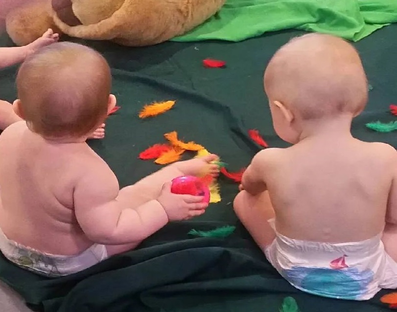 kaksi vauvaa istuu lattialla vaipoissaan