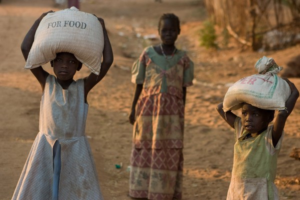 Tytöt kantavat jauhosäkkejä Sudanissa.