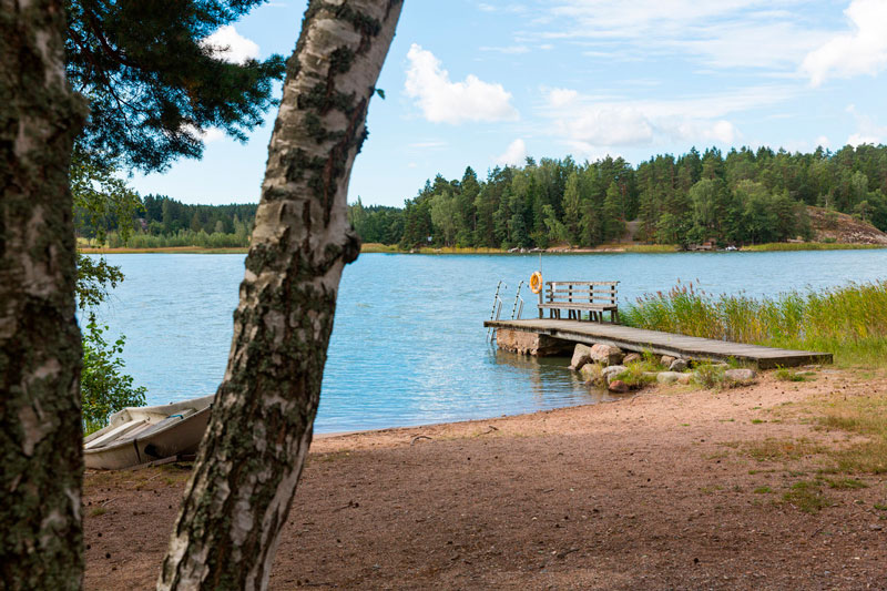 Ulkokuva Pyölinrannan leirikeskuksesta. Hiekkaranta ja laituri kesäisessä säässä.