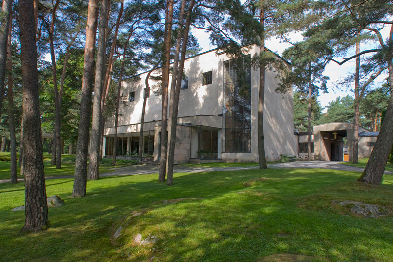 Ylösnousemuskappeli Vaalea, moderni rakennus mäntyjen keskellä.