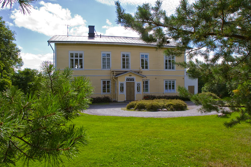 Hennalan seurakuntakoti Keltainen, kaksikerroksinen puutalo, jossa on kuisti ja ristikkoikkunat.