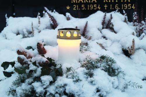 Kynttilä lumisella haudalla.