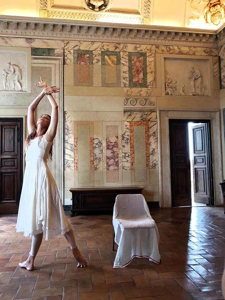 Vaaleaan mekkoon pukeutunut nainen tanssii roomalaisessa huoneessa