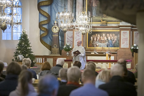 Ihmisiä jumalanpalveluksessa Piikkiön kirkossa ja alttarilla oleva pappi.