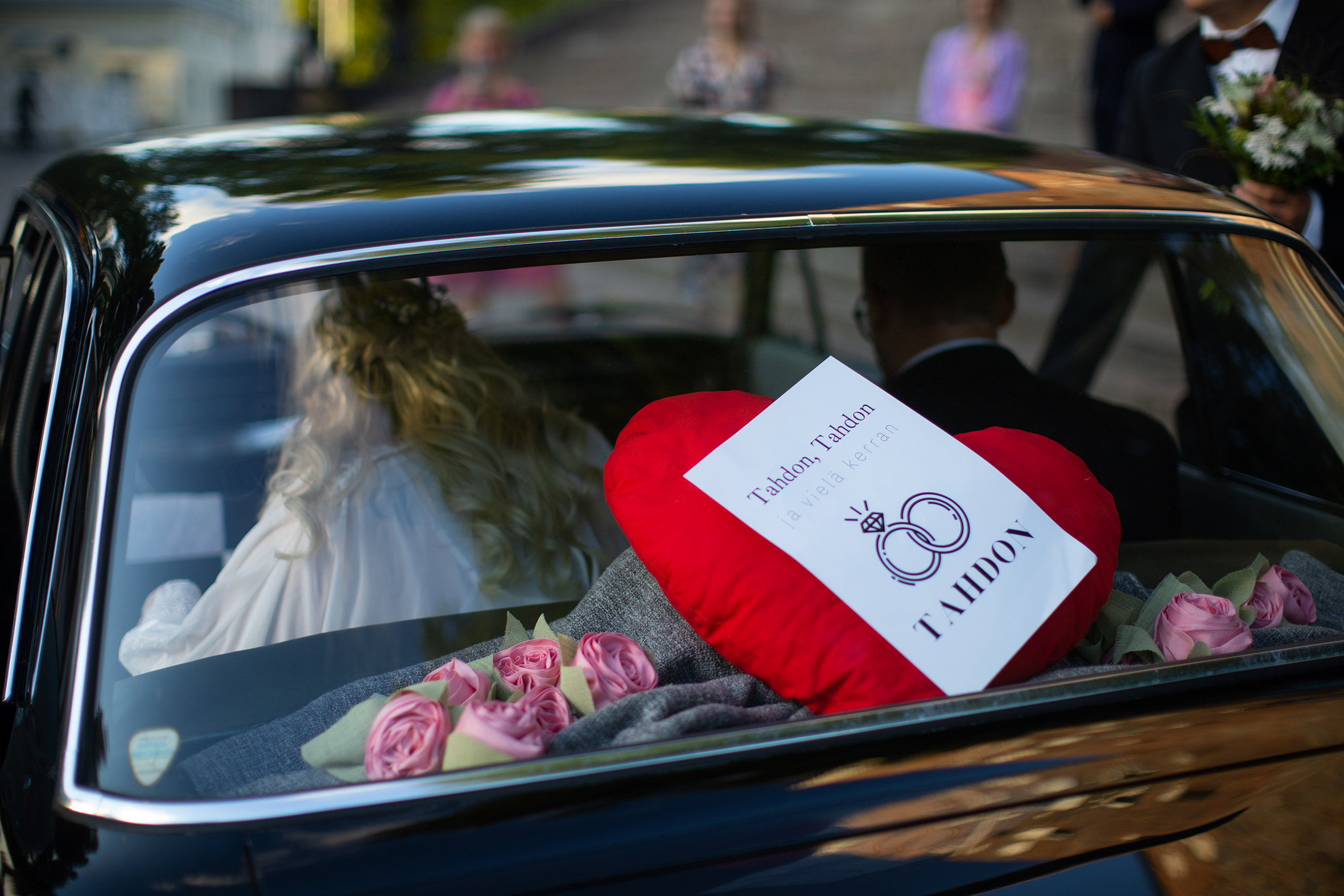 Hääauto, tahdon-kyltti ja pariskunta takapenkillä.