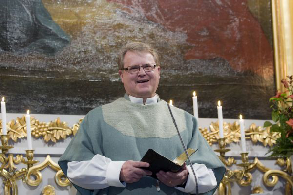 Heimo Rinne Tuomiokirkon alttarilla, käsikirja kädessä. 
