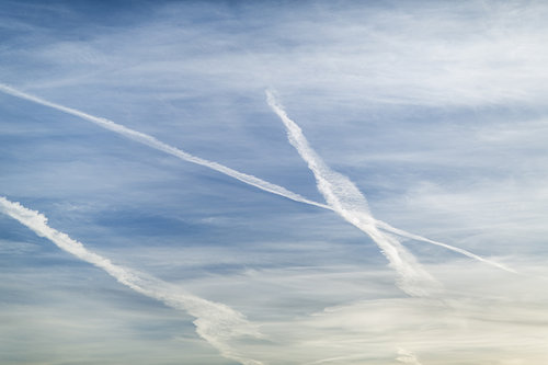 Lentokoneen viivat risteävät taivaalla.