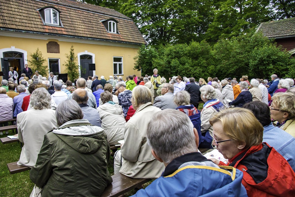 Juhannusjuhlan vieraita Maarian pappilan sisäpihalla takaa päin kuvattuna.