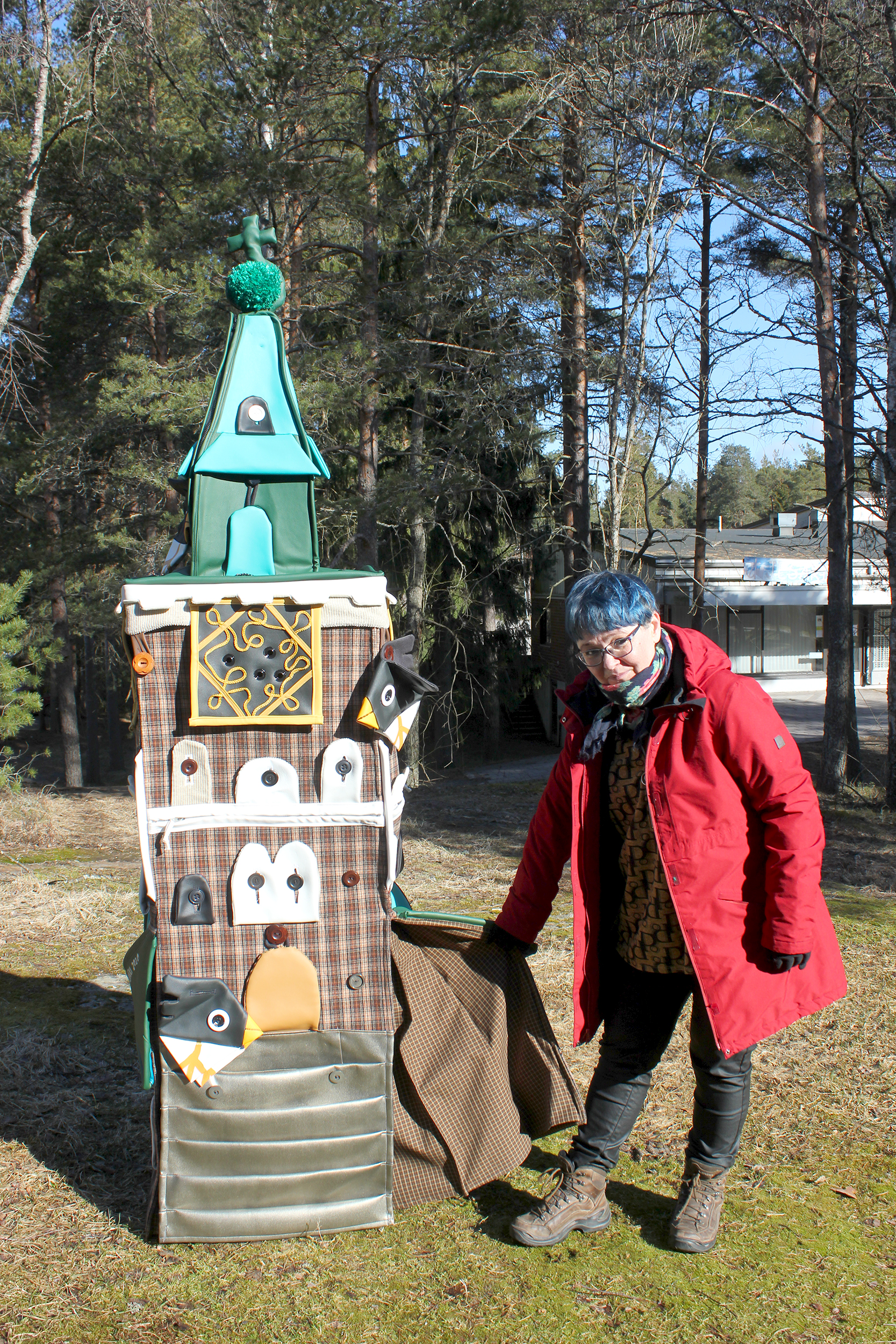 Mari Metsämäki seisoo värikkään reinokankaasta, tekonahasta ja samettikankaasta tehdyn yli kaksi metriä kor...