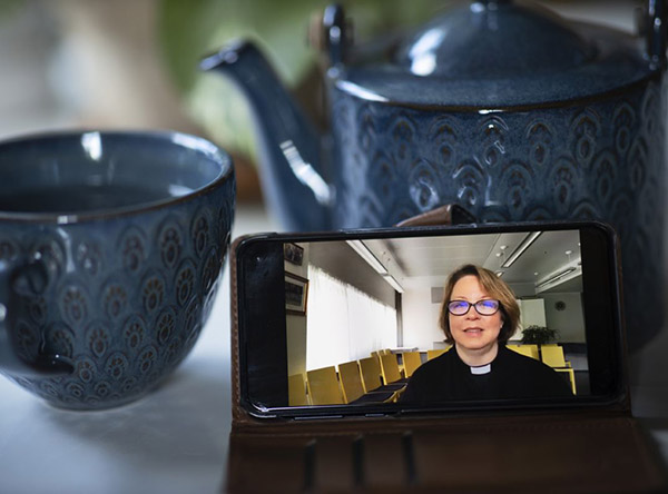 Kännykän näytöllä pappi vilkuttaa. Teksti: