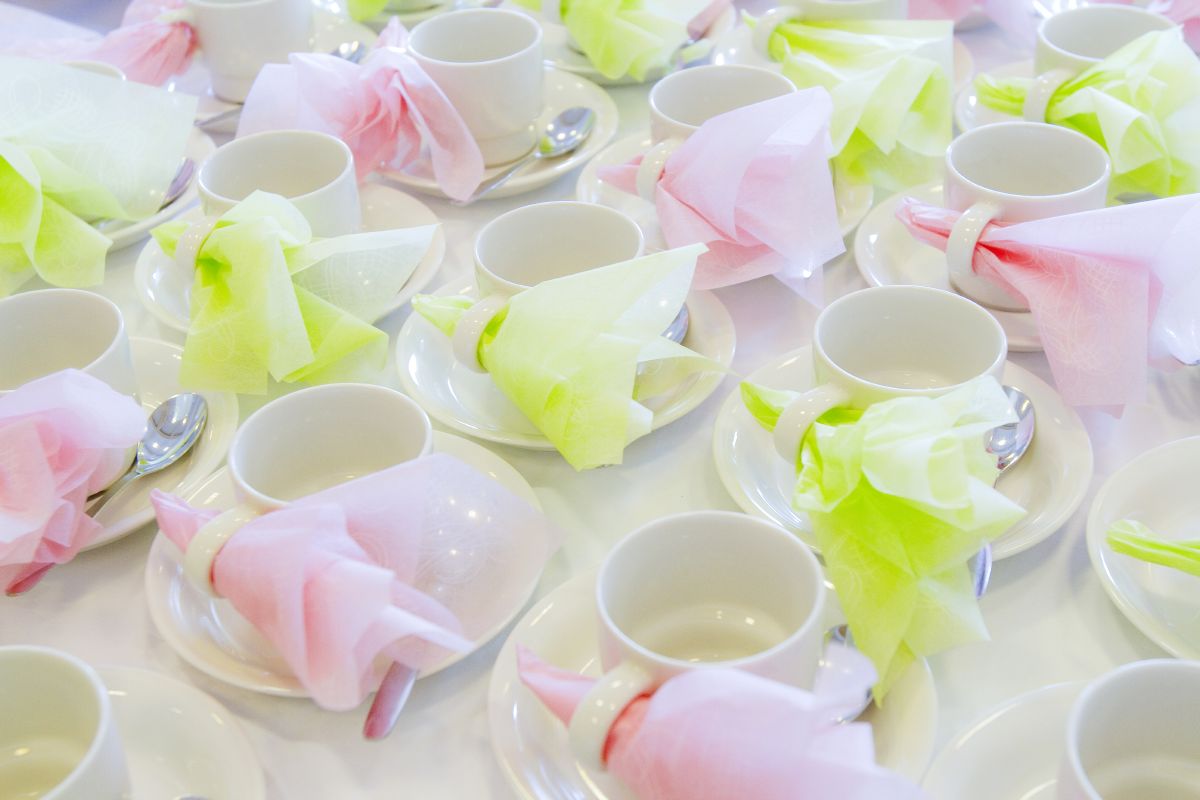 Pöydällä kahvikuppeja vaaleanpunaisilla ja vihreillä serveteillä.
