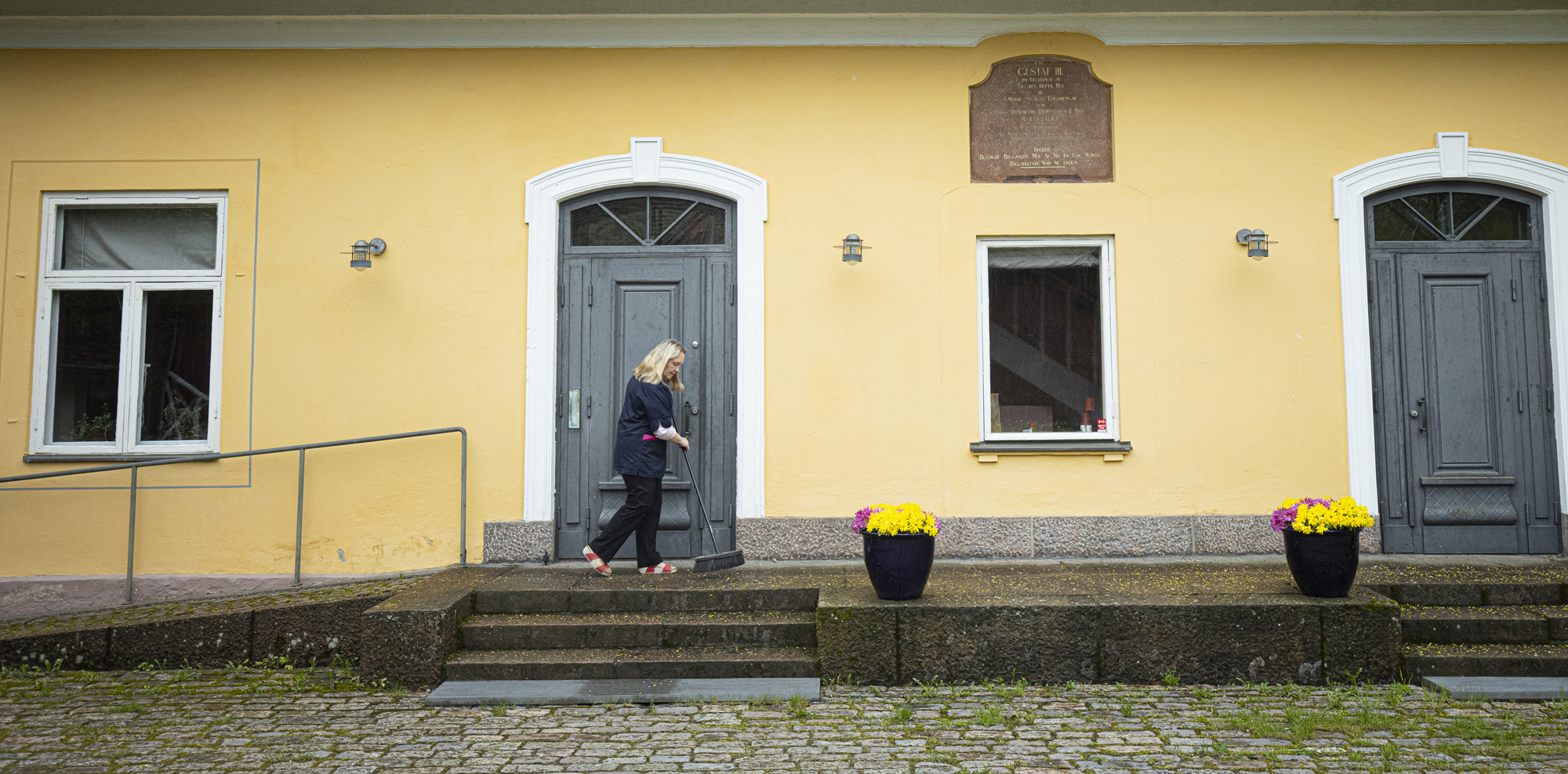 Maarian pappila ulkoapäin kuvattuna. Vahtimestari Sirpa Rantala lakaisee pappilan edustaa.