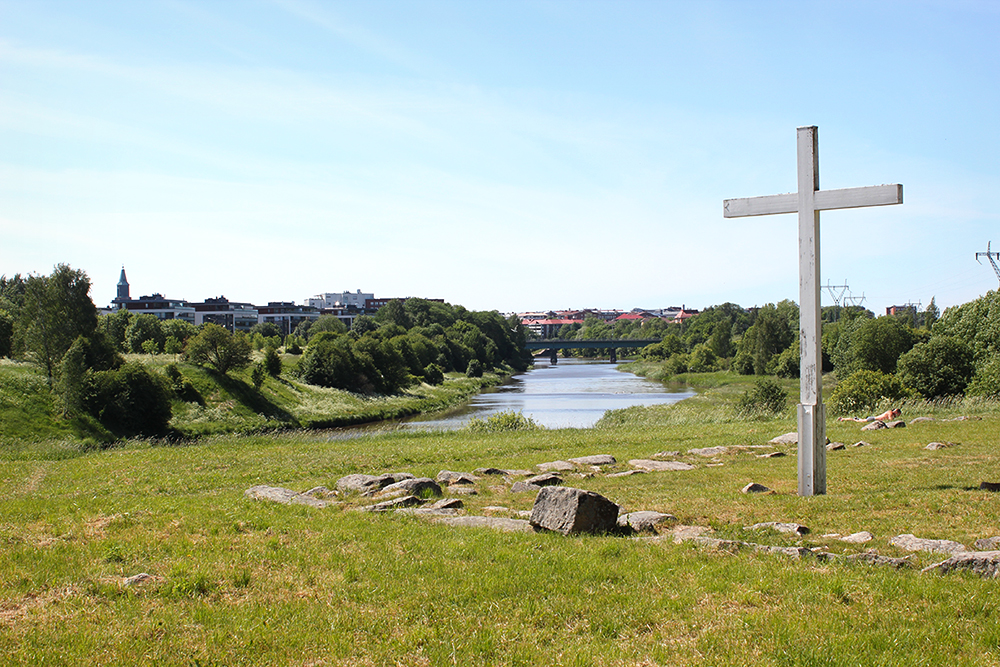Koroisten risti etualalla, taustalla Aurajoki ja Tuomiokirkon tornin huippu