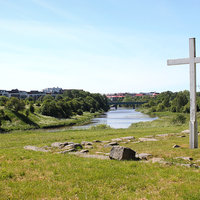 Koroisten risti entisen piispankirkon paikalla, taustalla nykyinen Tuomiokirkko