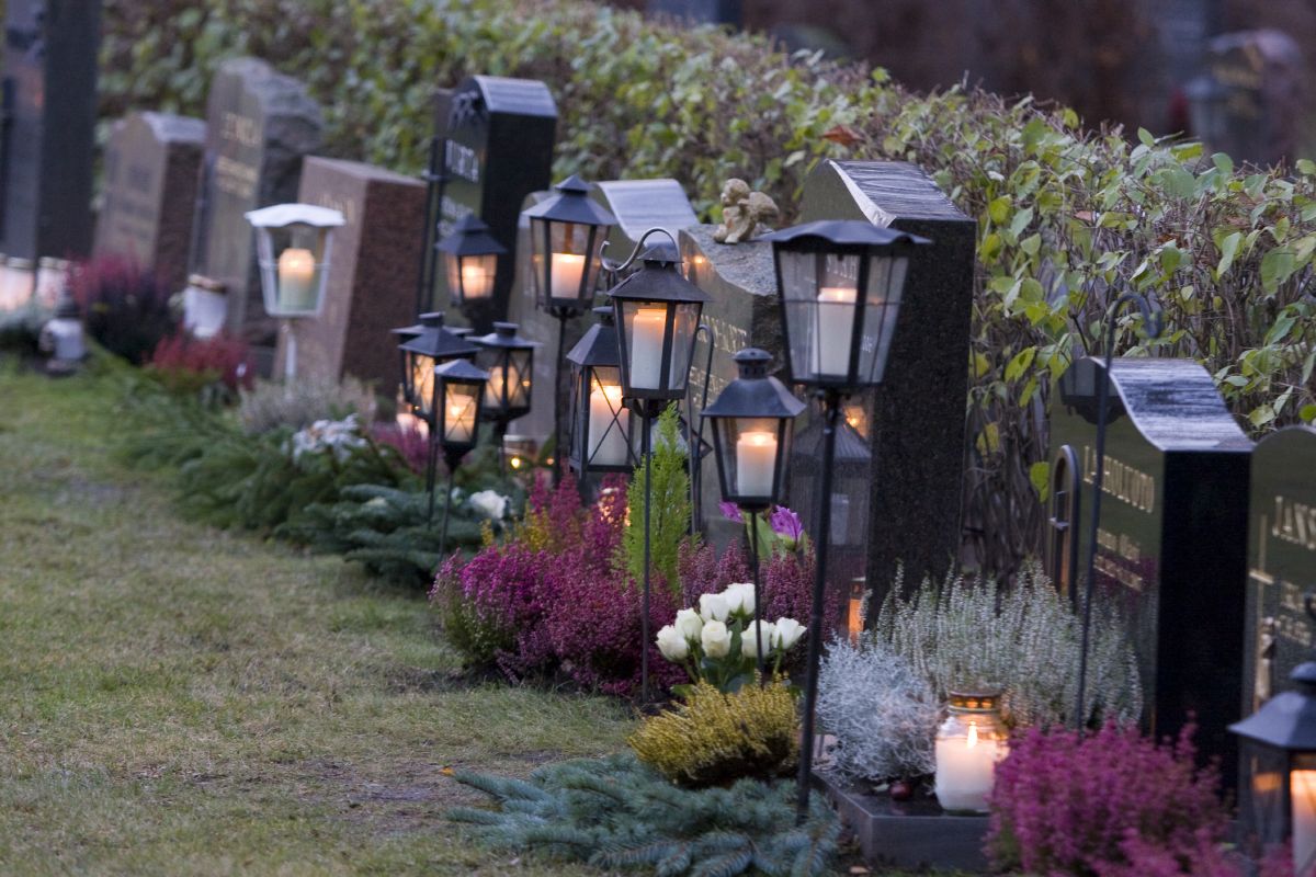 Kynttilät palavat lyhdyissä hautausmaalla.