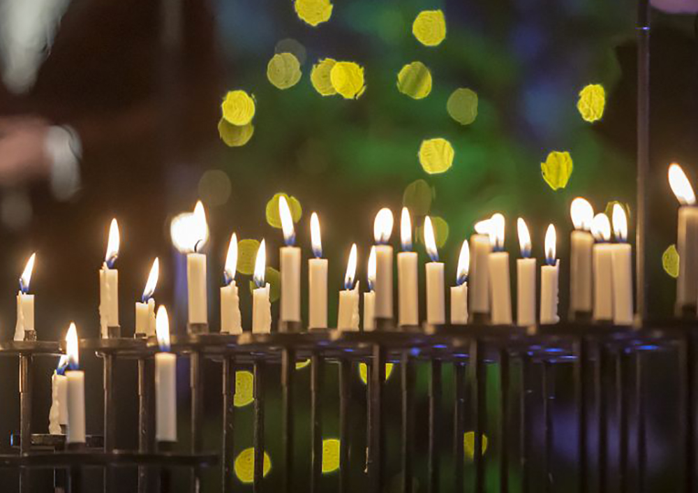 Kynttilät palavat Tuomiokirkon kynttelikössä, taustalla joulukuusen koristeita. Kuva Timo Jakonen.