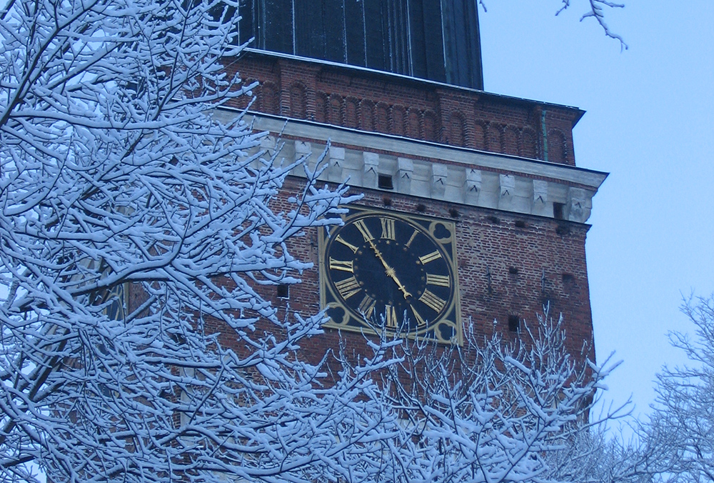 Tuomiokirkon tornin aikakello lumisessa maisemassa.