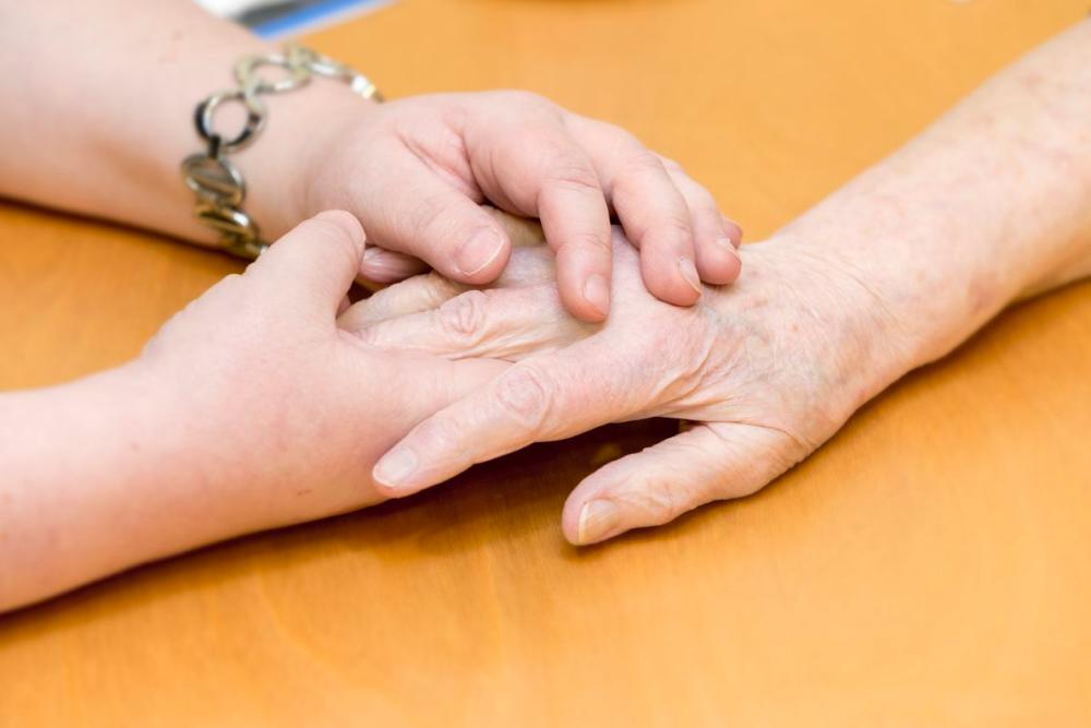 Vanhuksen käsi, josta pitää kiinni toinen ihminen molemmilla käsillä.